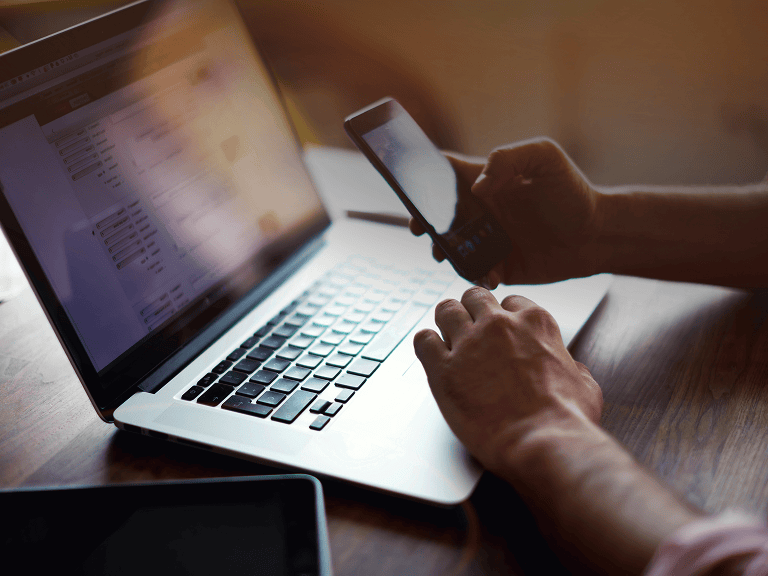 Early market engagement shown by a supplier completing a registration form on a laptop while checking a phone for updates